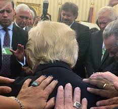 Photo as seen from behind of ministers laying hands on President Trump