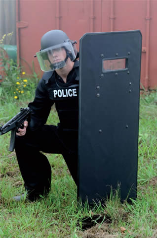 Picture of a police riot shield with a kneeling officer behind it